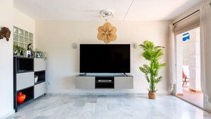 Un salon moderne avec un téléviseur à écran plat, un élément décoratif mural et une plante en pot.