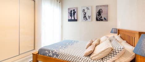 A bedroom with a bed, a nightstand, a lamp, and artwork on the wall.