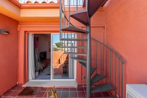 A spiral staircase leading to a balcony with a view of a garden.