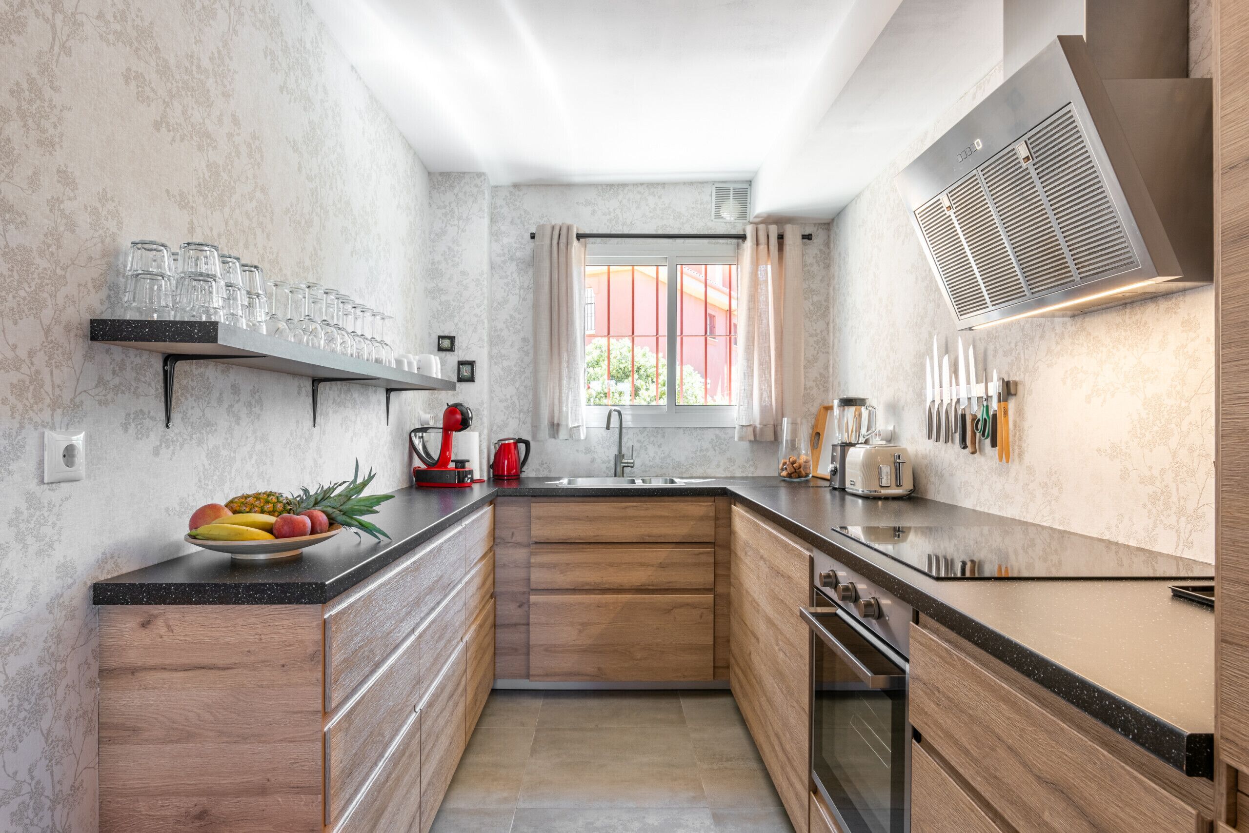 Una cocina moderna con armarios de madera, encimera negra y ventana con cortinas.