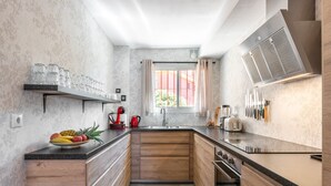 Een moderne keuken met houten kastjes, een zwart aanrecht en een raam met gordijnen.