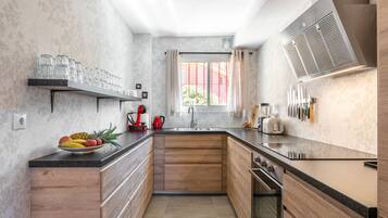 Una cocina moderna con armarios de madera, encimera negra y ventana con cortinas.