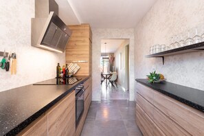 Een moderne keuken met een zwart aanrecht, houten keukenkastjes en een inbouwoven.