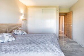 Een slaapkamer met een bed, een kledingkast en een nachtkastje.