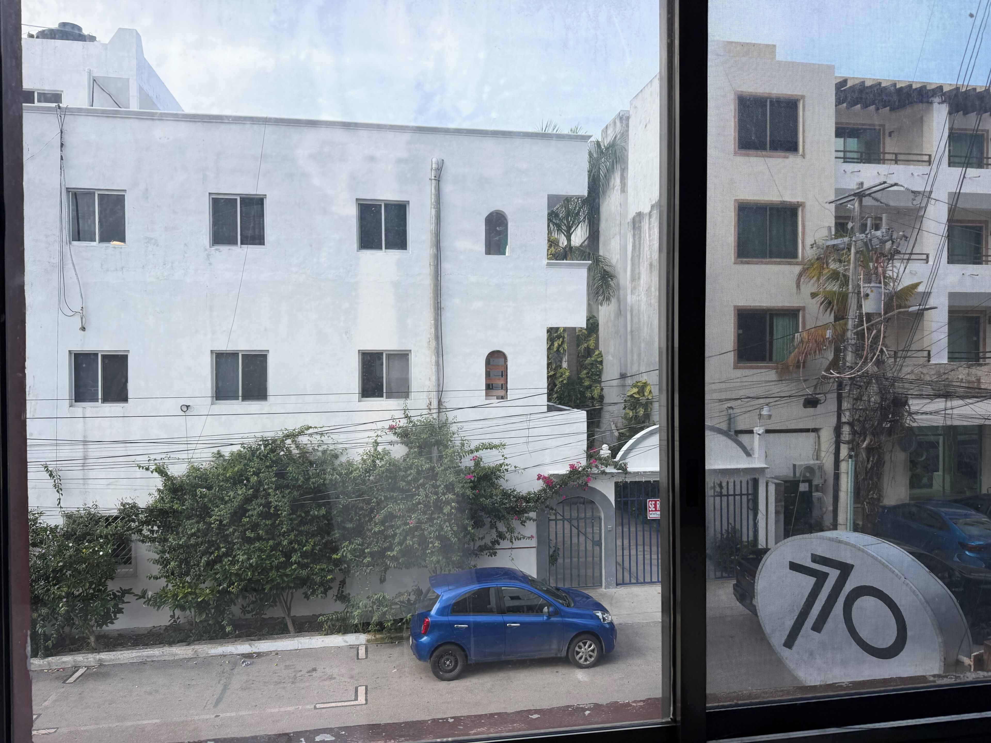 A building with multiple windows and a blue car parked in front.
