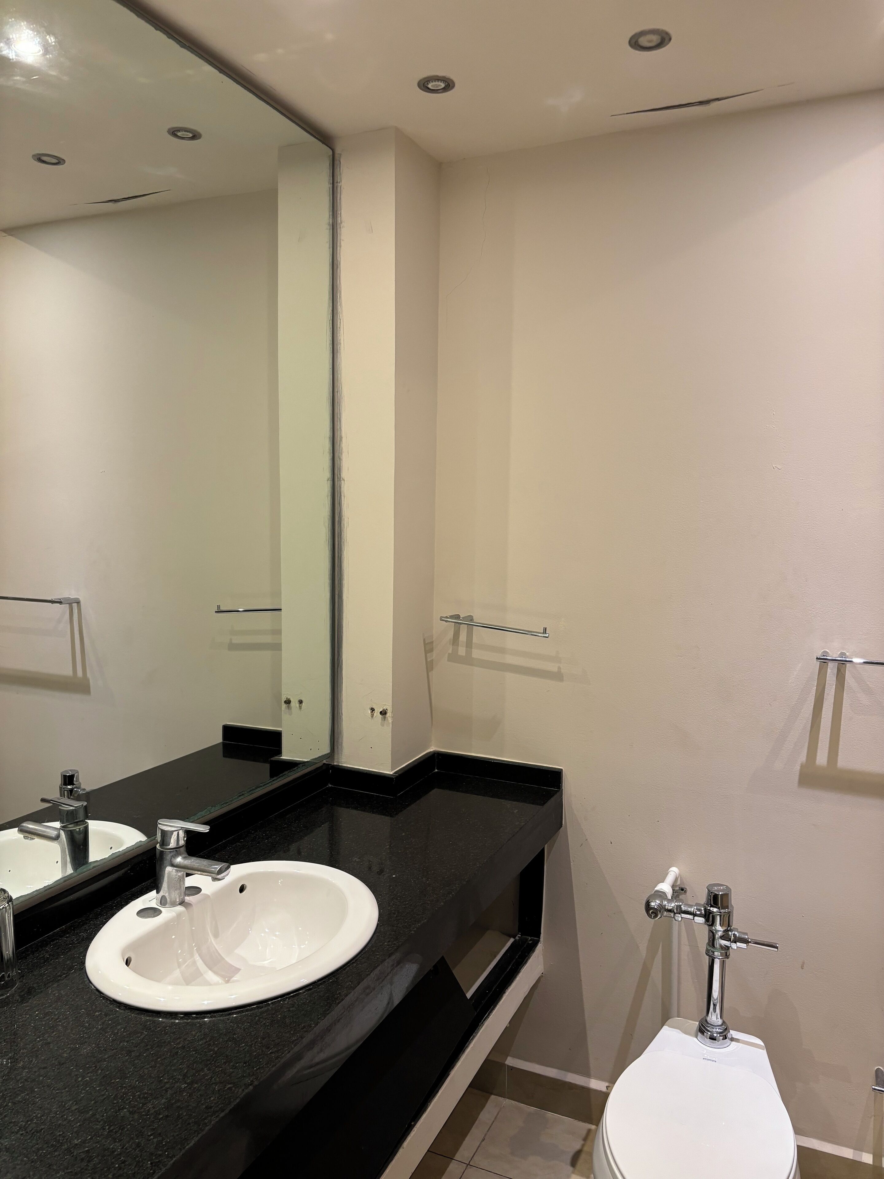 Un baño con lavamanos blanco, espejo e inodoro.