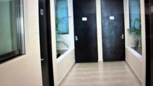 A hallway with two doors, a tiled floor, and a window with a plant. - 770 Apartments (Playa del Carmen)