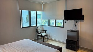A modern hotel room with a large bed, a chair, a TV mounted on the wall, and a small cabinet. - 770 Apartments (Playa del Carmen)