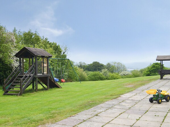 A playground with a swing set and a small wooden structure with stairs. - 2 bedroom accommodation in Dunterton, near Tavistock (Dunterton, near Tavistock)