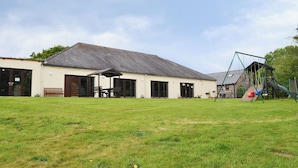 Un bâtiment doté d’un patio couvert, d’une balançoire et d’une pelouse.