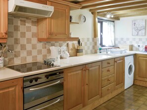A kitchen with wooden cabinets, a built-in oven, a dishwasher, and a washing machine.