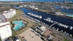 A marina with boats docked, a swimming pool, and a large building with multiple floors. - Barefoot Havens 325 - Golf, Shopping, Dining, Pool (North Myrtle Beach)