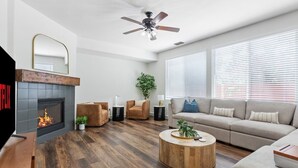 Un salon moderne avec une cheminée, un ventilateur de plafond, un canapé et une table basse.
