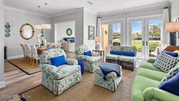 A spacious living room with a dining area, a green sofa, and patterned armchairs. - Sawgrass Country Club - 26 Tifton Way - Stunning Golf Course Views! (Ponte Vedra Beach)