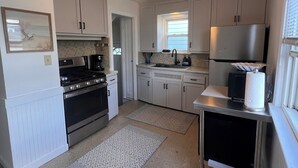 A modern kitchen with white cabinets, a stove, oven, and a ceiling fan.