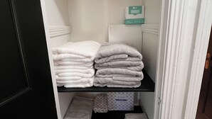 A storage area with shelves holding folded towels and toilet paper.