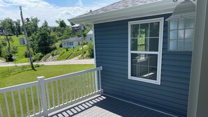 A blue house with a white porch railing and a large window.