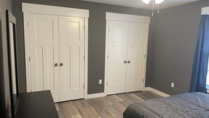 A bedroom with two white wardrobes, a bed, a black nightstand, and a ceiling fan.
