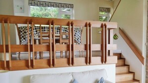 Una escalera con barandillas de madera y un sofá blanco con cojines a cuadros.