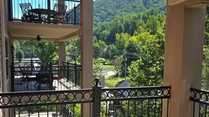 A balcony with a view of a green landscape and a distant building. - Creek and Mountain Views.  Can’t ask for more (Gatlinburg)