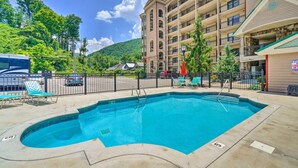 A swimming pool with lounge chairs, a fenced area, and a multi-story building in the background. - Creek and Mountain Views.  Can’t ask for more (Gatlinburg)