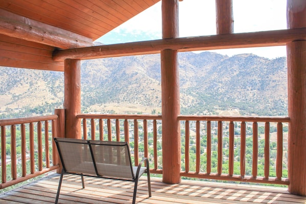 Una terraza de madera con un banco que da a un paisaje montañoso.
