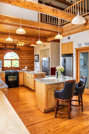 A spacious kitchen with wooden cabinets, a central island, and bar stools.