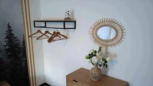 Een hoek van een kamer met een houten kast, een spiegel en een wandplank met een klein decoratief object.