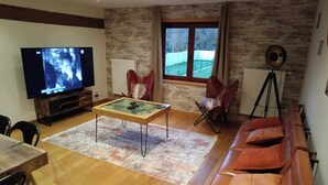 Een woonkamer met een televisie, een salontafel, een bank en een stoel.