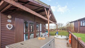 Une cabane en bois dotée d’un patio couvert comprenant un jacuzzi et une table avec une bouteille.