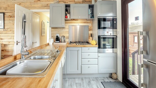 Une cuisine moderne avec des éléments en bois, des appareils en acier inoxydable et une vue sur l’extérieur.
