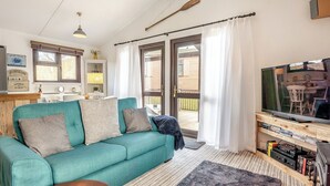 Un salon chaleureux avec un canapé de couleur turquoise, une table basse en bois et un téléviseur à écran plat posé sur un meuble en bois.