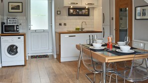 Une cuisine compacte équipée d’un lave-linge, d’un four à micro-ondes et d’un coin repas avec une table et des chaises.