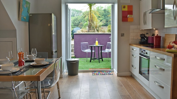 Une cuisine moderne avec un coin repas, une vue sur l’extérieur et un petit patio.