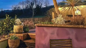Un espace patio agrémenté de plantes en pot, d’un banc en bois, d’une lanterne et d’un mur avec une fenêtre.