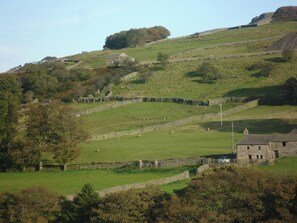 A rural landscape with stone walls, a stone building, and grazing sheep. - 2 bedroom accommodation in Gayle near Hawes (Gayle near Hawes)