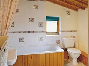 A bathroom with a bathtub, toilet, and a window with a curtain. - 2 bedroom accommodation in Gayle near Hawes (Gayle near Hawes)