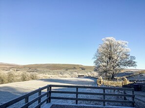 A wooden fence, a bench, and a frost-covered landscape with a tree and distant hills.