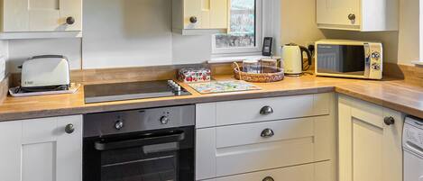 A modern kitchen with white cabinets, a built-in oven, a microwave, and a toaster.