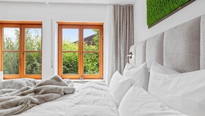 Ein Schlafzimmer mit einem großen Bett, zwei Fenstern und einer grünen Wanddekoration.