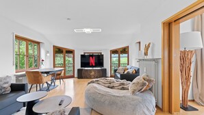 Ein modernes Wohnzimmer mit einem großen Flachbildfernseher, einem gemütlichen Sofa, einem runden Couchtisch und einer komfortablen Sitzecke.