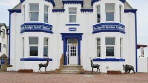 Un edificio de dos plantas con letreros que indican 'Melvin Lodge Guest House' y 'Portpatrick Seaview Apartments'.