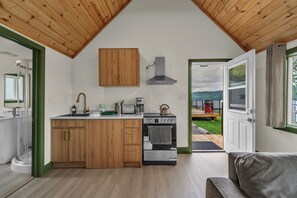 A modern kitchen with wooden cabinets, a built-in stove, and a view of the outdoors. - White Birches Cottages (Dwight)