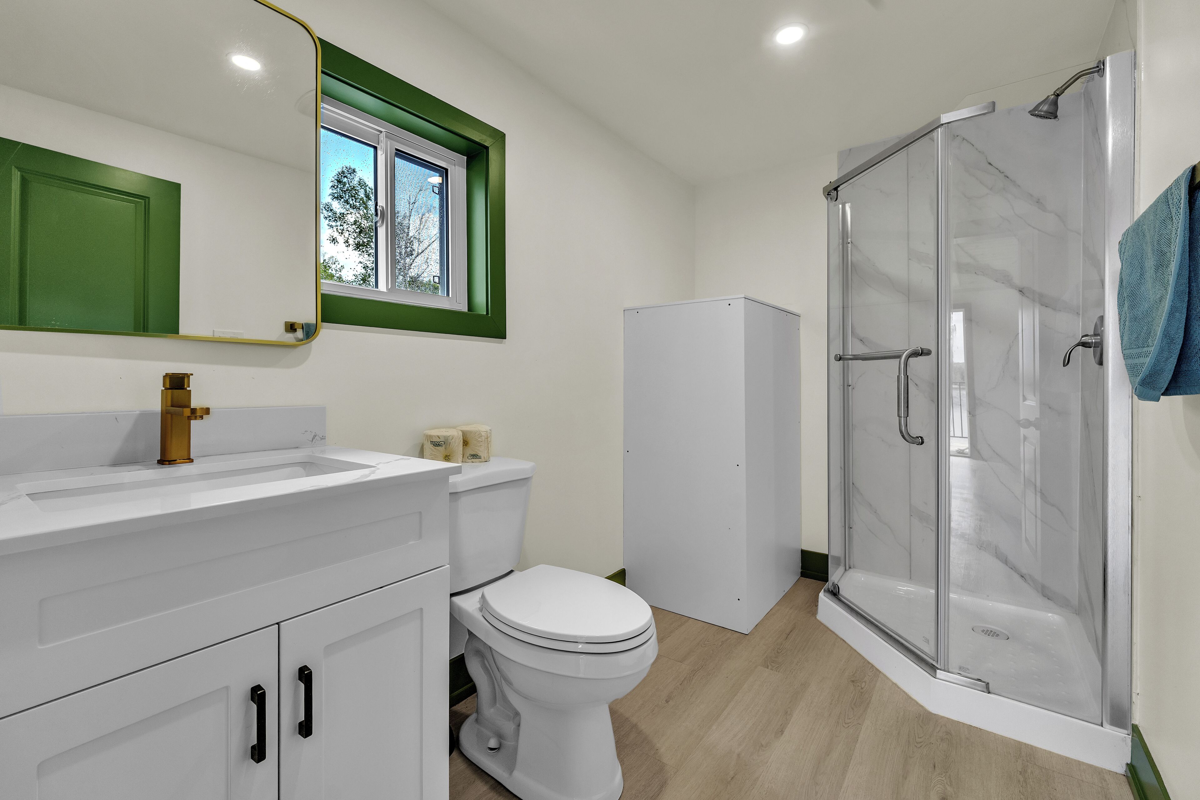 A bathroom with a white sink, toilet, and shower enclosure.