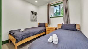Habitación doble con dos camas, una mesita de noche, una ventana con cortinas y un cuadro en la pared.
