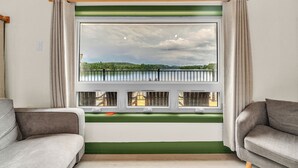 Una habitación con un ventanal grande, dos sofás grises, una pared de acento verde y un techo de madera.