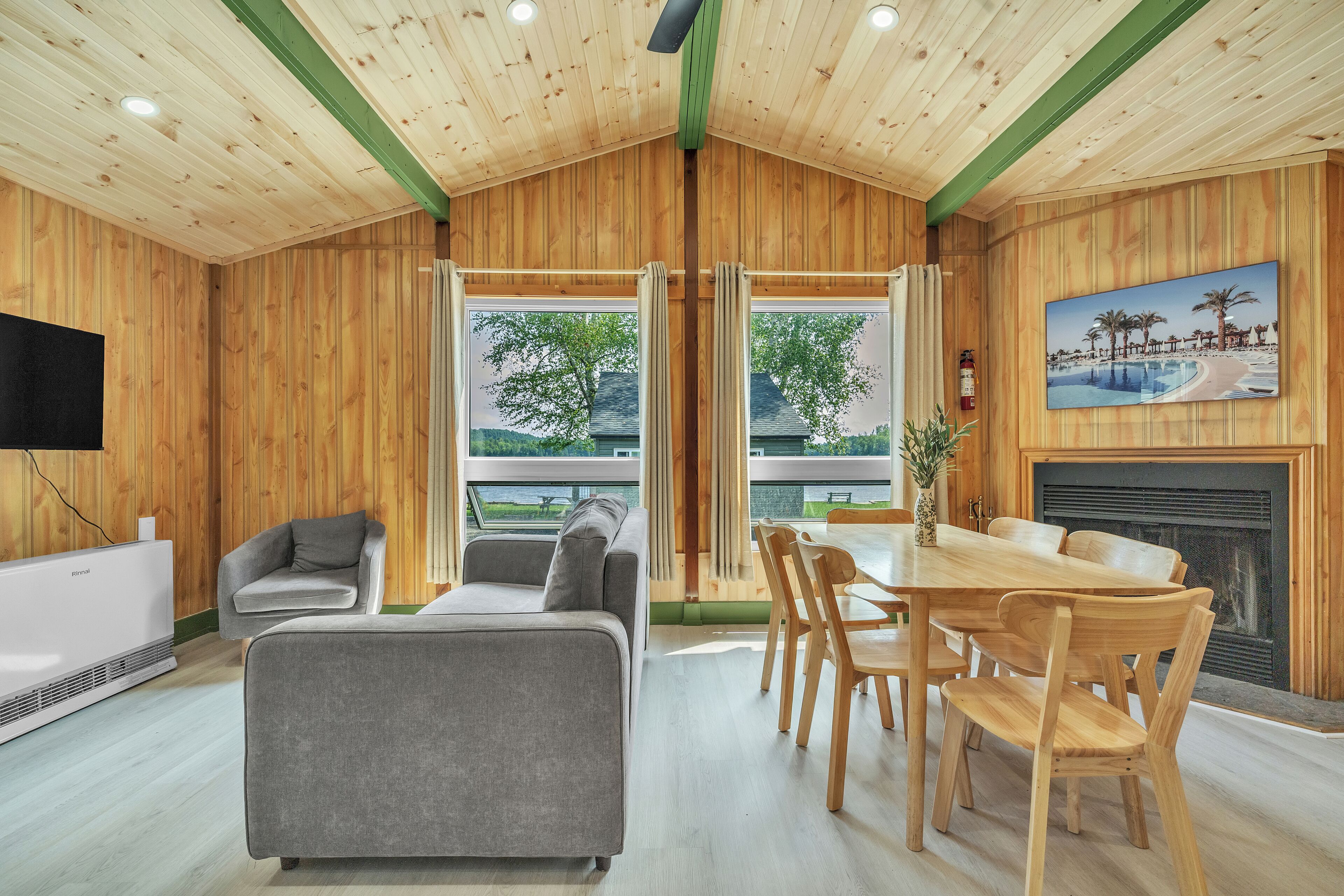 A wooden interior with a dining area, sofas, and a fireplace.