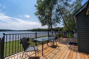A deck with a table and chairs overlooking a lake. - White Birches Cottages (Dwight)