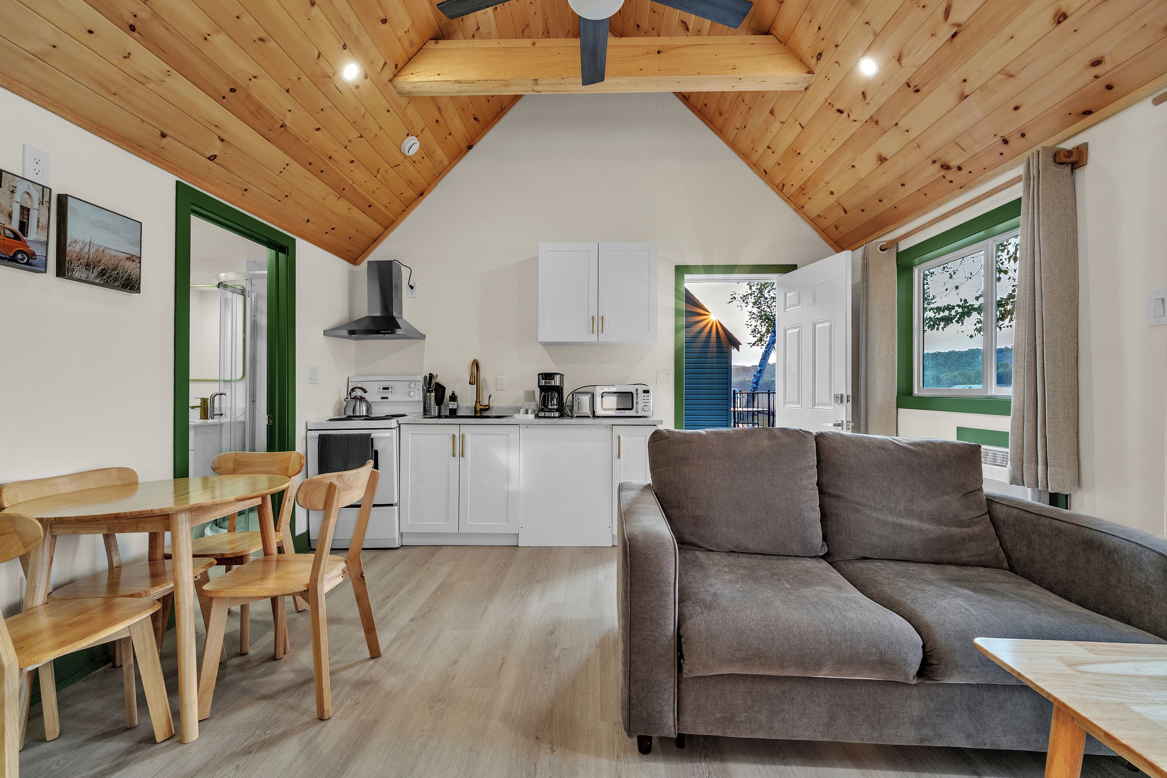 Een moderne keuken met witte kastjes, een eethoek met houten meubels, en een grijze bank.