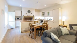 Una cocina moderna con armarios blancos, una isla central y un comedor con sillas y una mesa de madera.